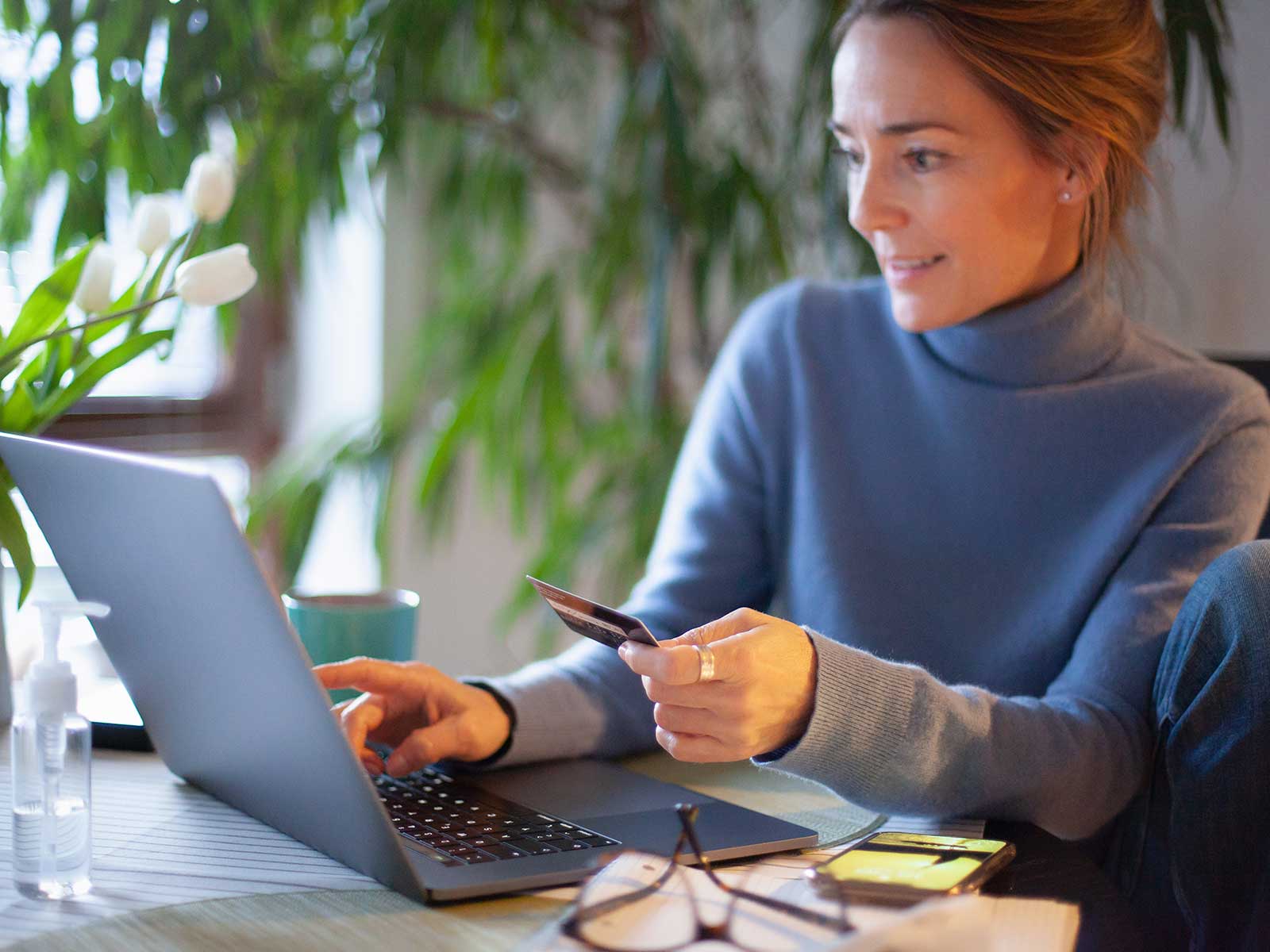 Kvinder sidder ved skrivebord med PC og tilmelder betaling online.