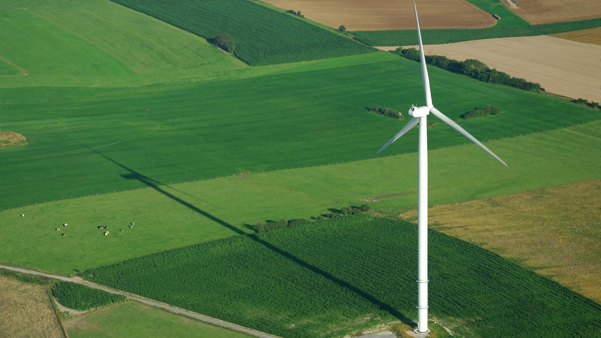 En vindmølle står midt på en mark – set oppefra i fugleperspektiv. VE-certificeret strøm er vedvarende energi, der er produceret af vindmøller. Dyk ned i hvordan vindenergi fungerer, og hvordan strømmen kommer ind i elnettet.