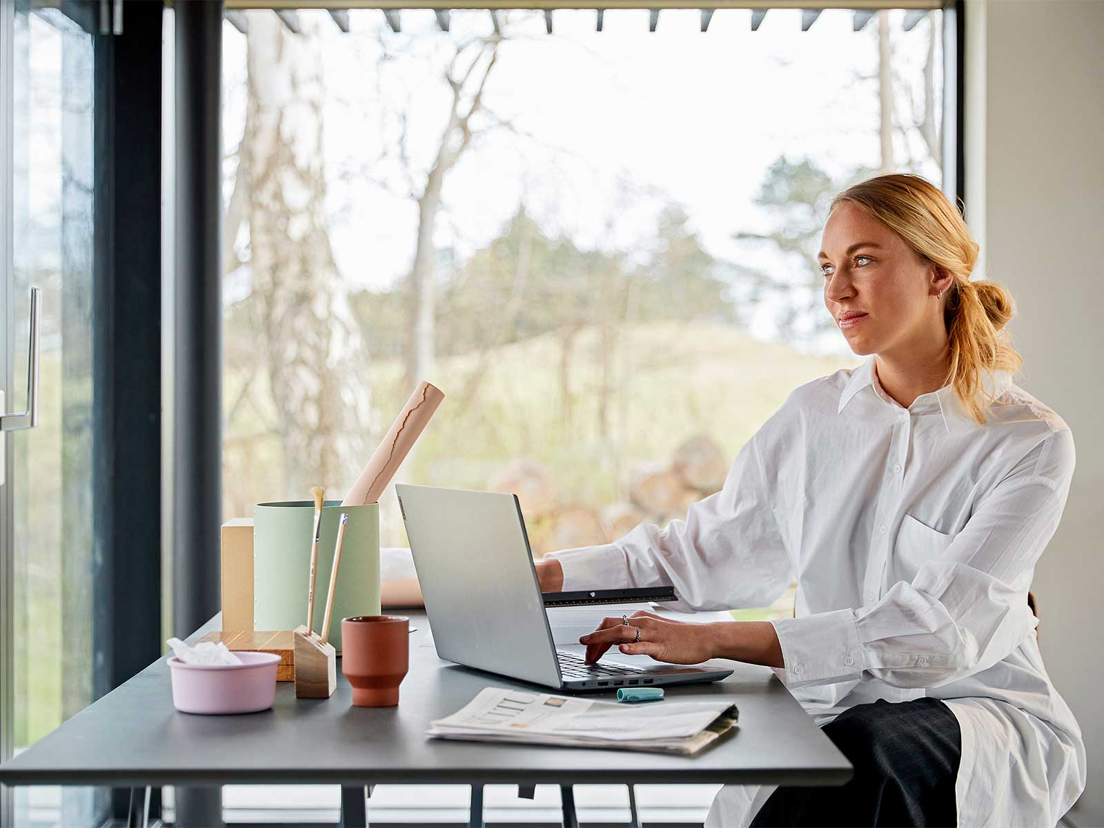 Kvinde sidder ved skrivebord med pc foran sig