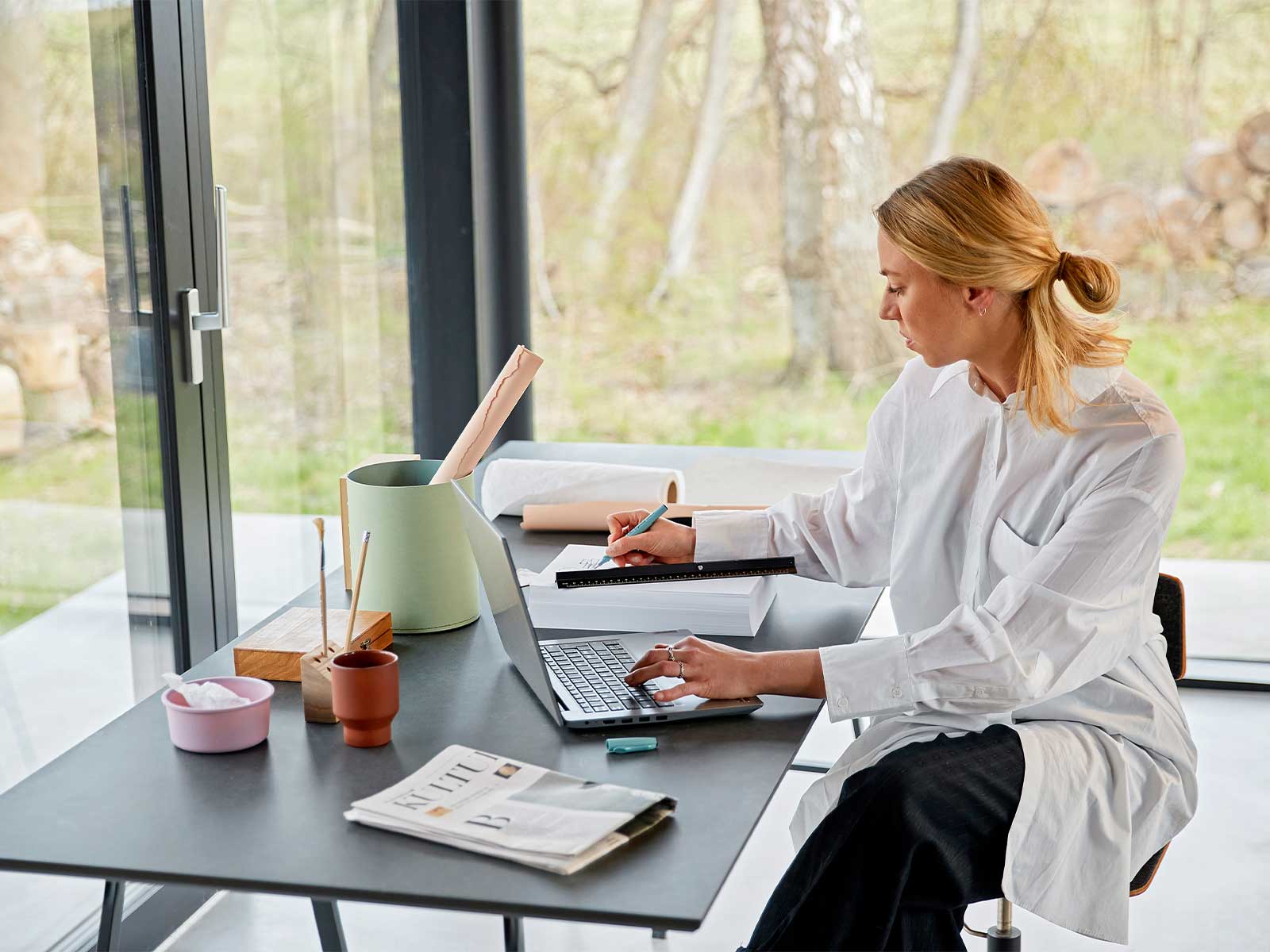 Kvinde sidder ved skrivebord og arbejder på bærbar pc. Hun kan arbejde effektivt fordi hun har fibernet i Fredericia på kontoret og fibernet i Fredericia derhjemme.
