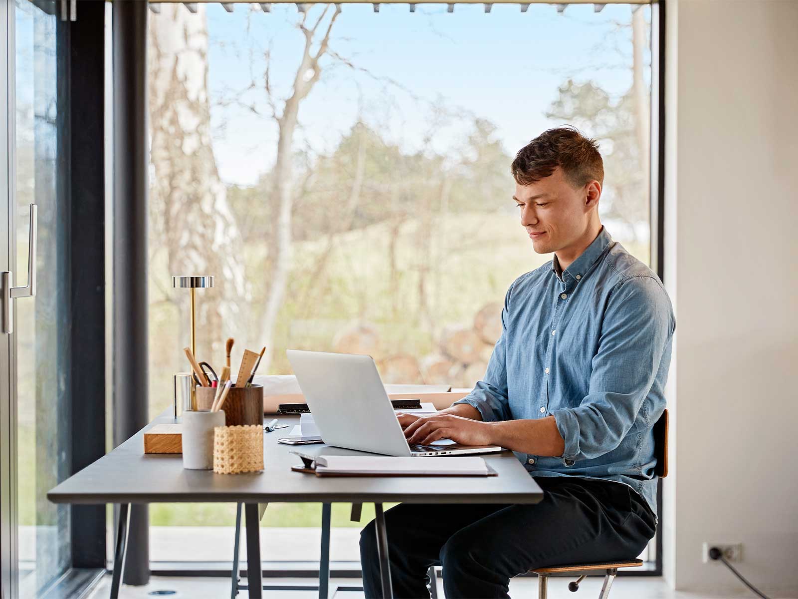 Ung mand sidder og arbejder på pc ved skrivebord