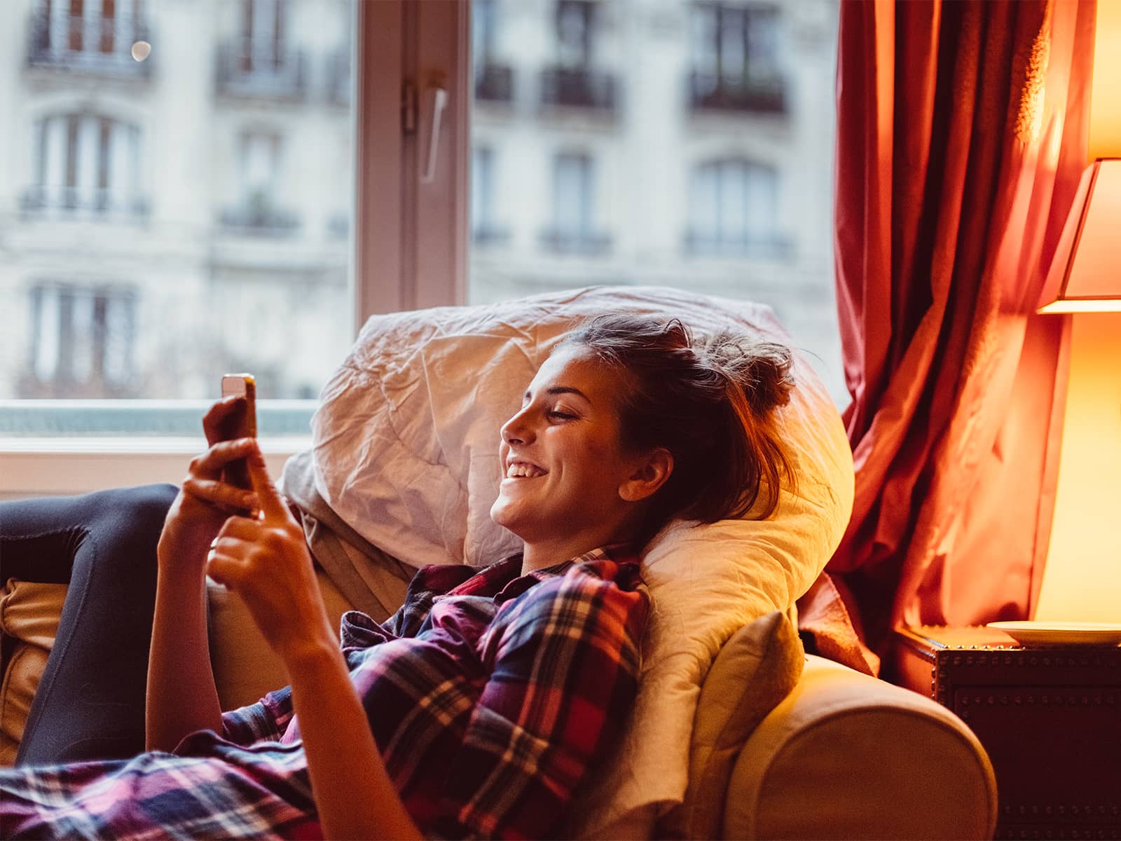 Kvinde ligger i sofa og surfer på mobilt internet på sin telefon. Hvad er mobilt bredbånd?