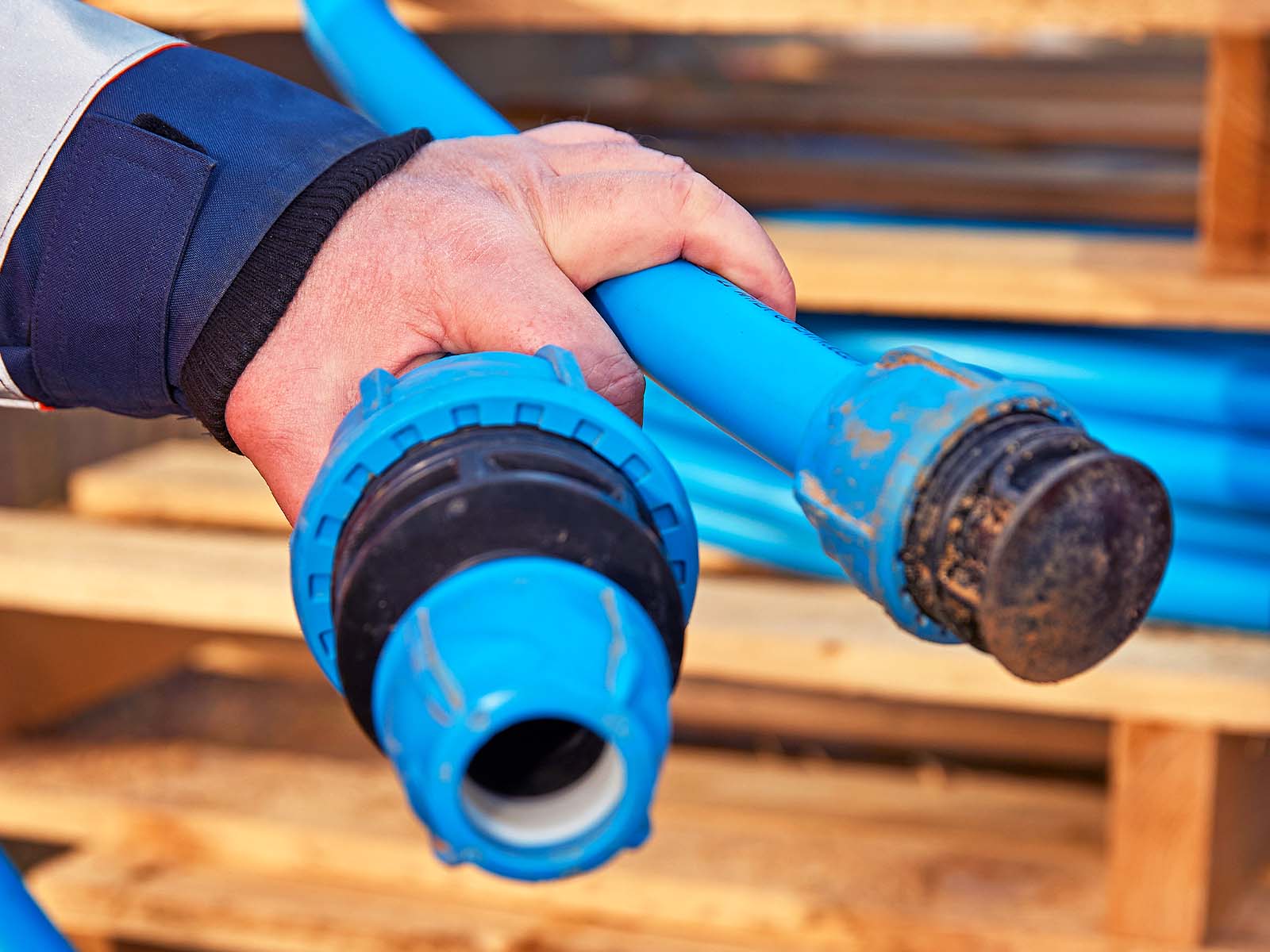 Hænder holder blå vandrør i hånden