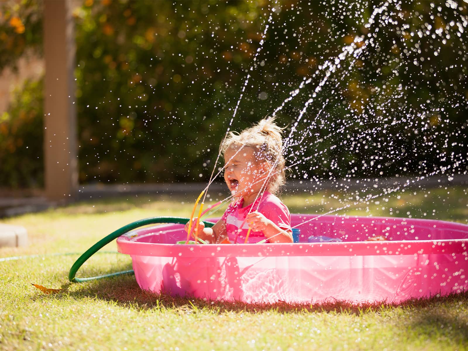 Vand i lyserødt badebassin i haven. Hvad koster det at fylde badebassinet op? 