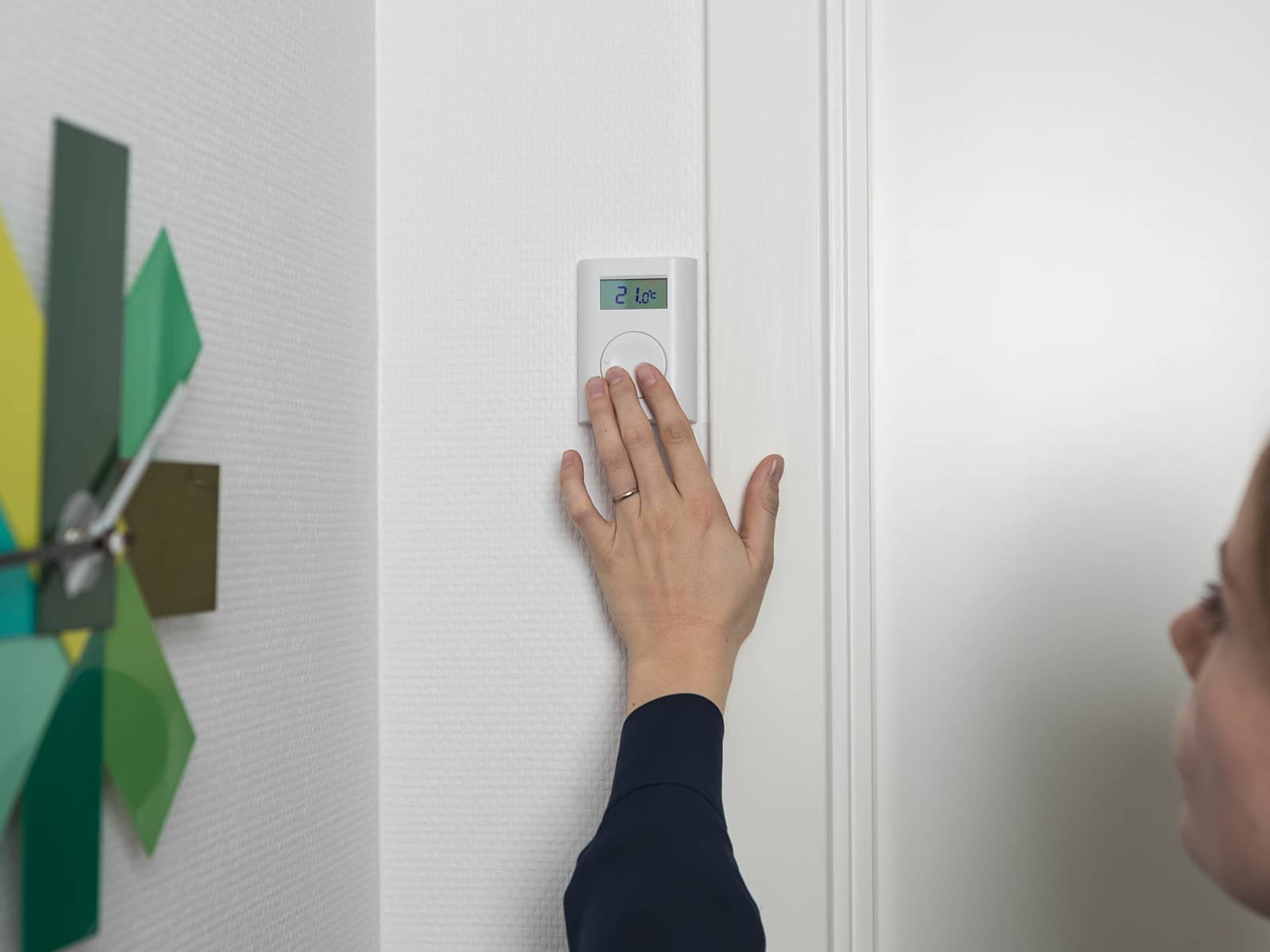 Hånd instiller temperatur på væghængt termostat