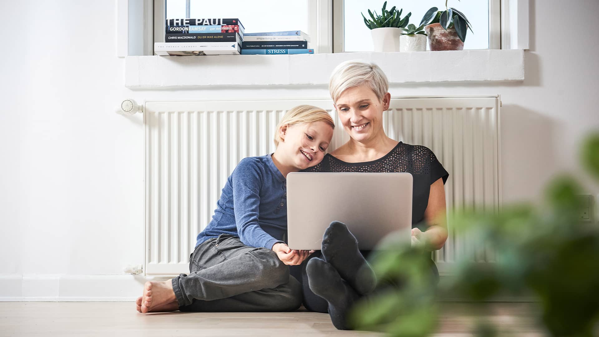 Mor og søn med pc foran radiator