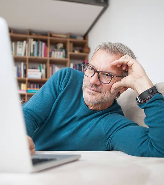 Mand ligger sidelæns og kigger ind i sin computer mens han er ved at logge ind på EWIIs selvbetjening. I EWIIs selvbetjening kan du nemt få overblik over dit forbrug af el, vand og varme. Samtidig får du adgang til en rækkekundefordele under 'Din Afspændingszone'.