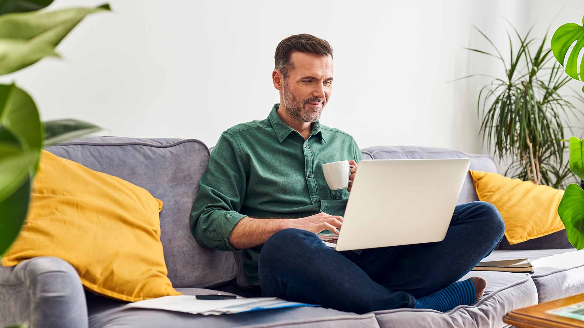 En tilfreds erhvervskunde sidder i sofa med bærbar pc i skødet.