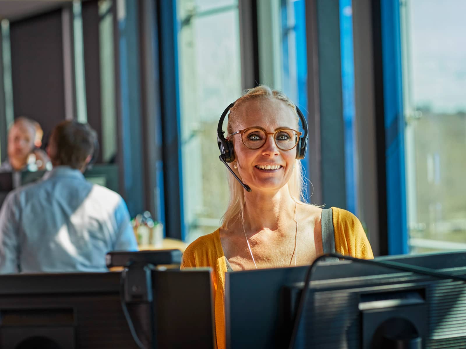 Kvindelig kollega taler i telefon og smiler ind i kameraet
