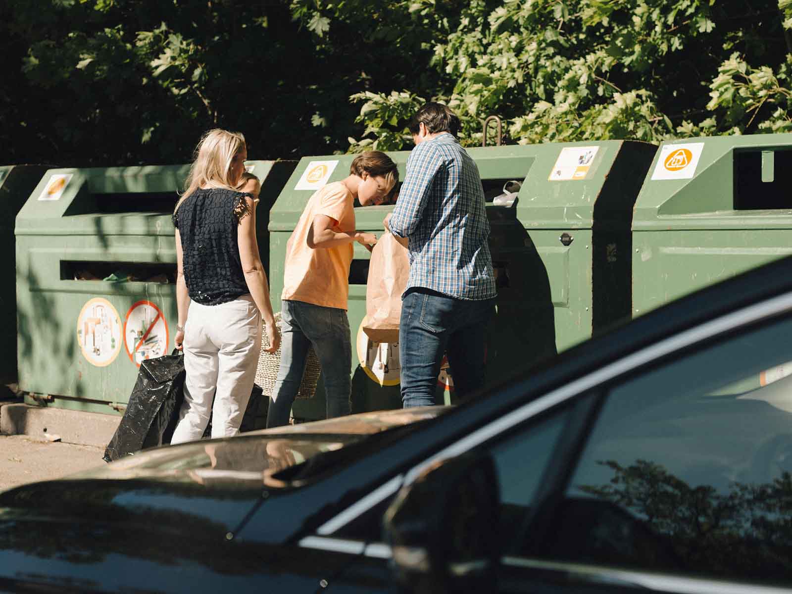 En familie er i gang med at sortere deres affald i containere.