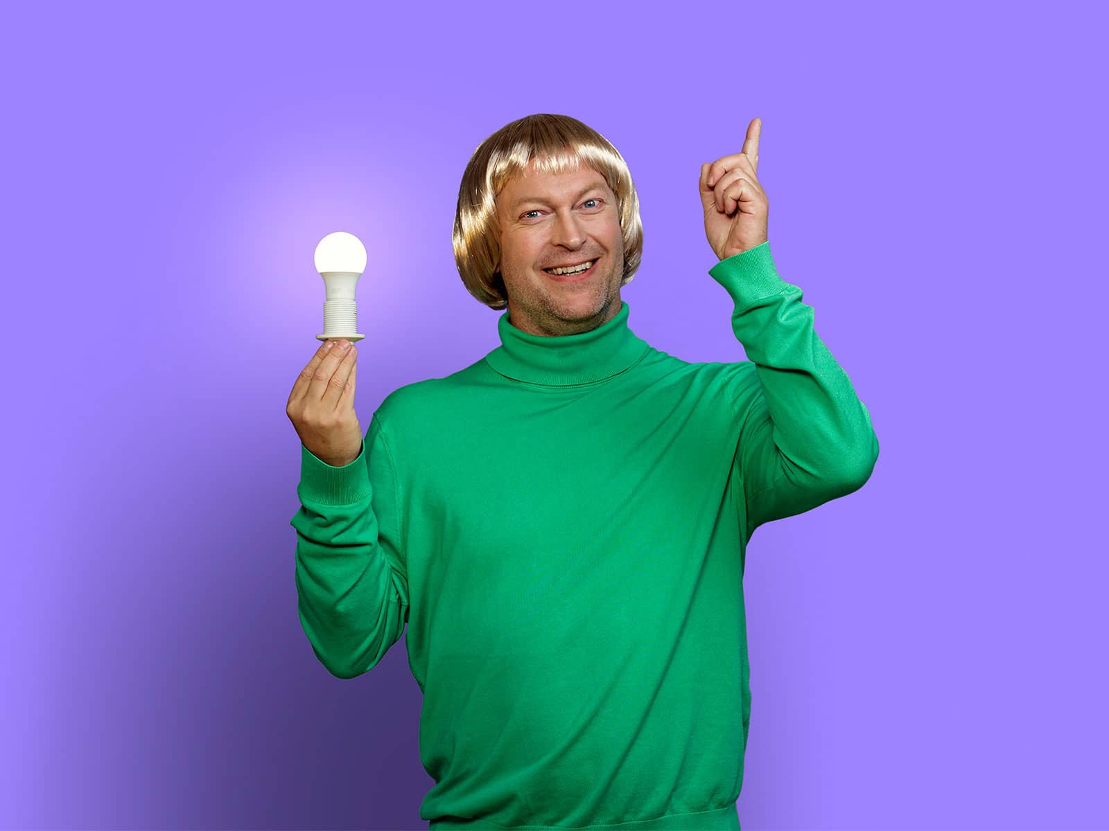 Mand har en tændt elpære i den ene hånd og peger op i luften med den anden hånd, da der er gået et lys op for ham.