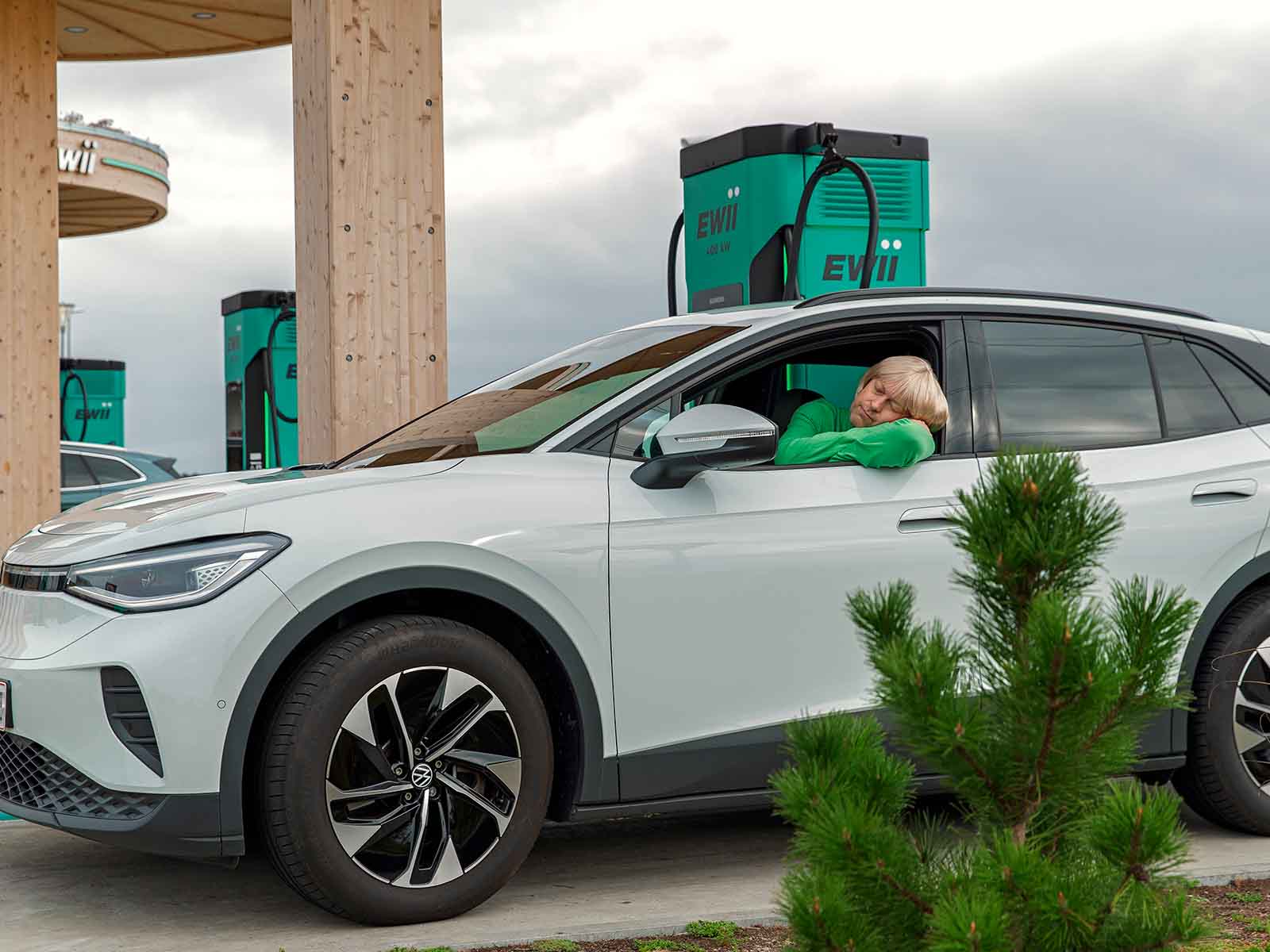 Mand tager en lur i bil, mens bilen lader ved en EWII lynladestation