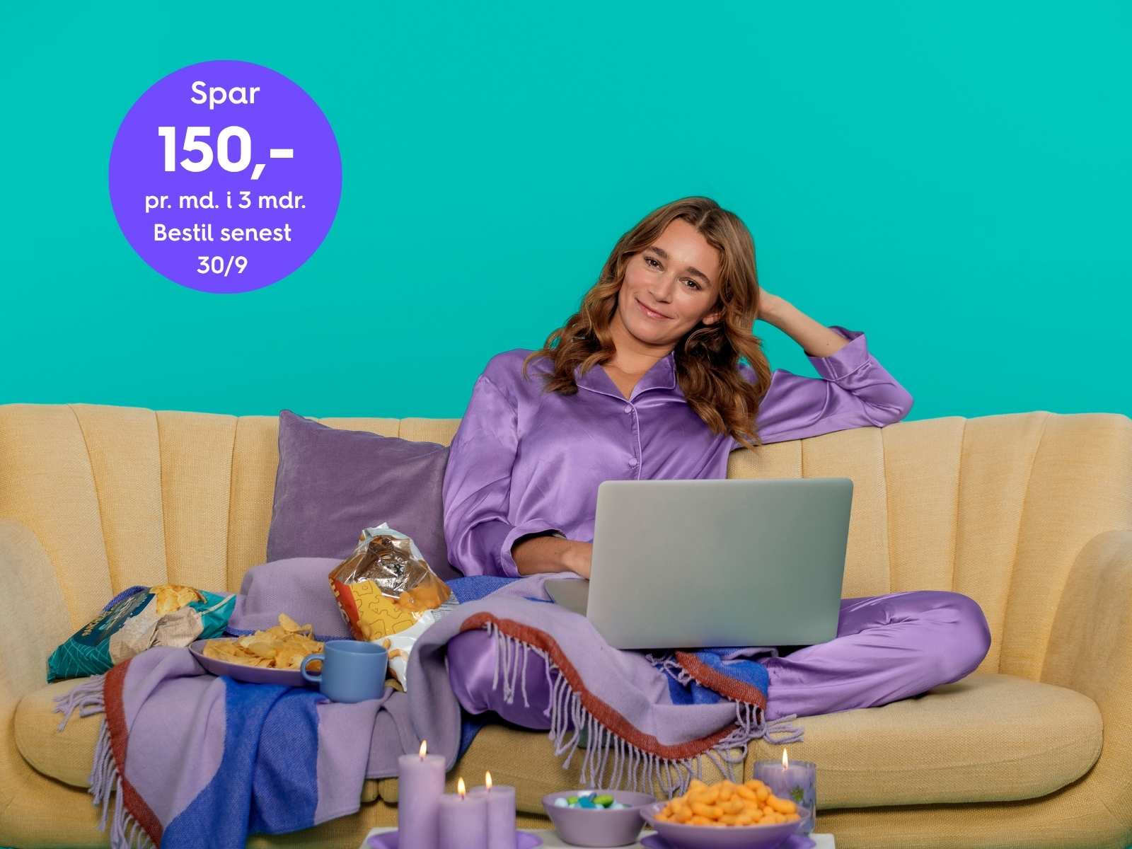 Kvinde sidder i sofa med pc, tæpper, chips og snolder og hygger sig. Hun er glad fordi hun har købt fibernet fra EWII.