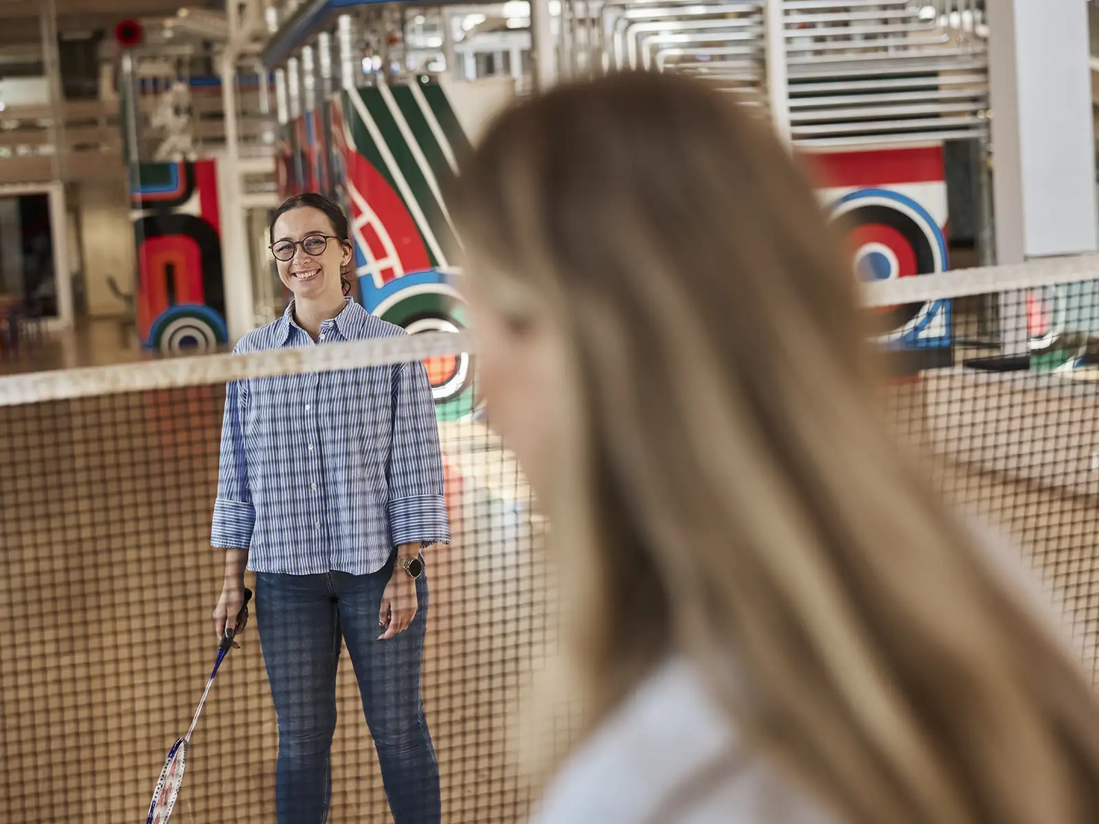 Smilende EWII medarbejder ved badmintonbane
