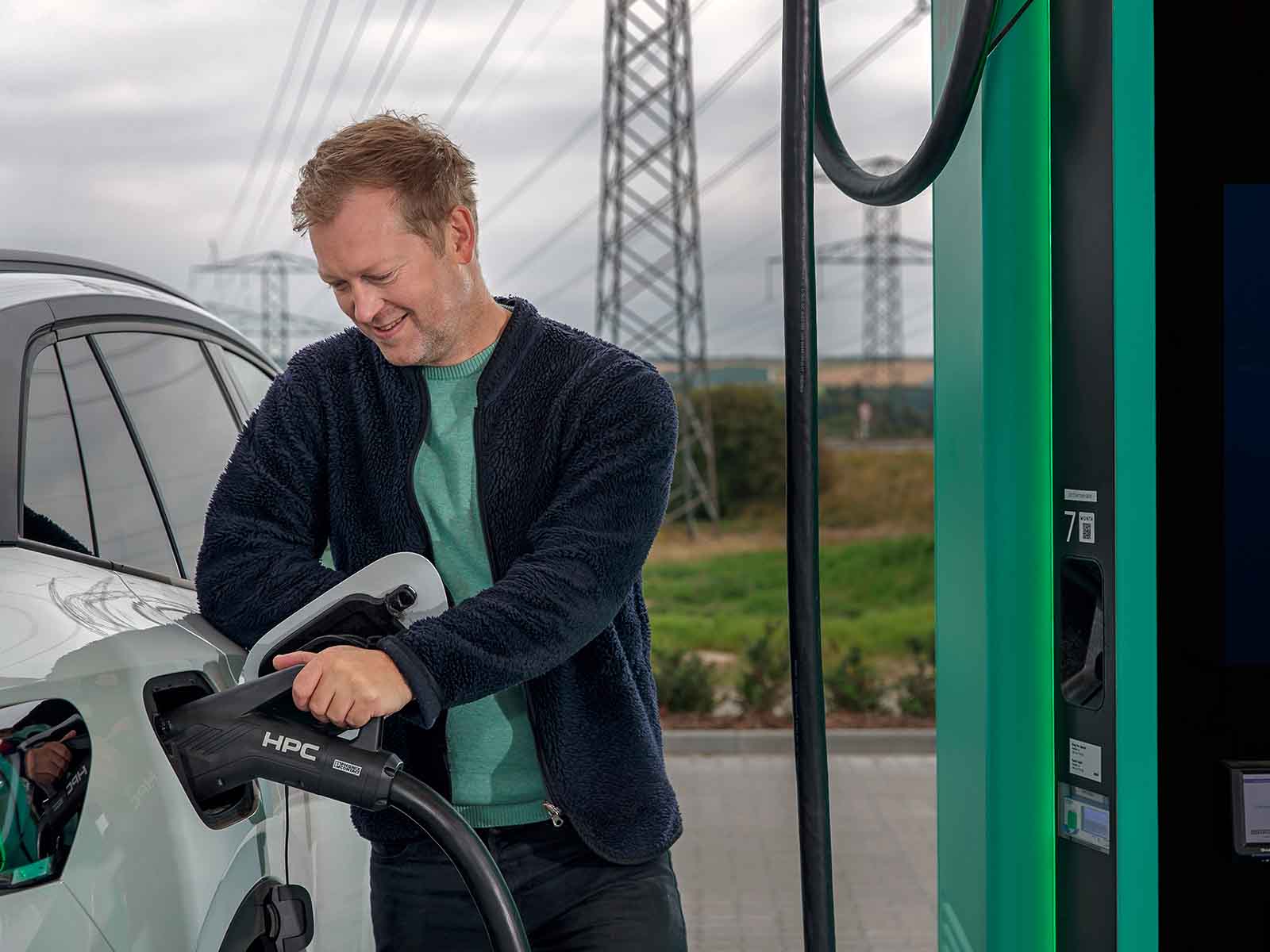 Mand tilslutter ladestik i sin elbil ved en EWII lynlader. Han har lade el fra EWII uden en ladeboks hjemme, men får 20 % laderabat på EWII offentlige ladepunkter.