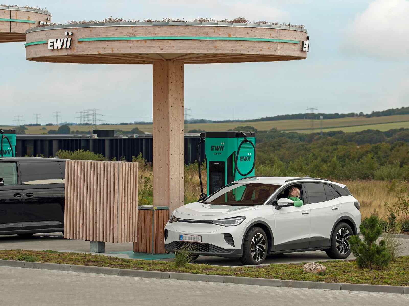 Mand får en ladelur i sin hvide bil mens den bliver lynladet ved EWIIs ladestation i Svenstrup.
