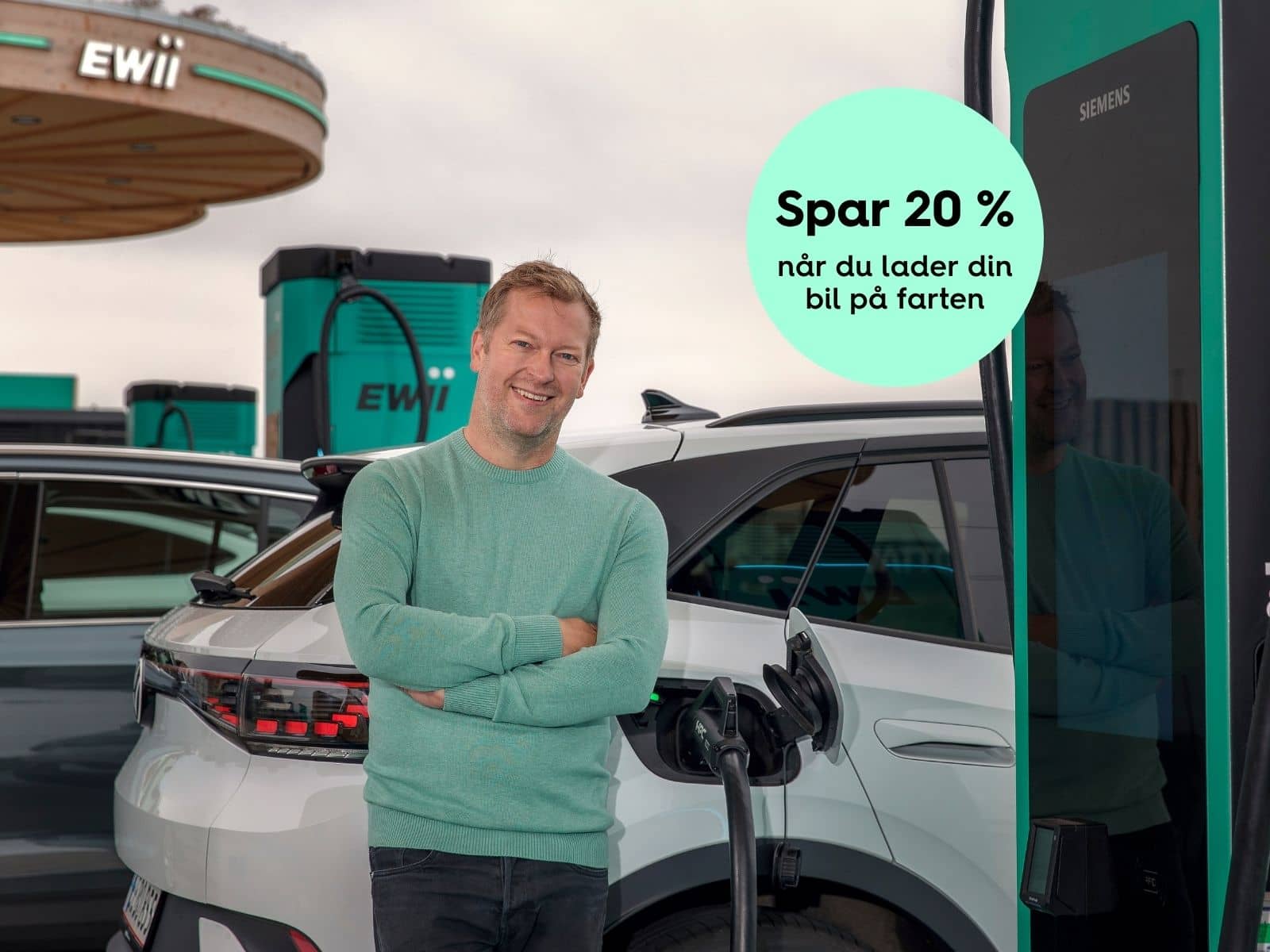 En mand står og lader sin elbil ved en EWII lynladestation. Og han er glad, da han som ladekunde hos EWII får 20 % rabat på farten.