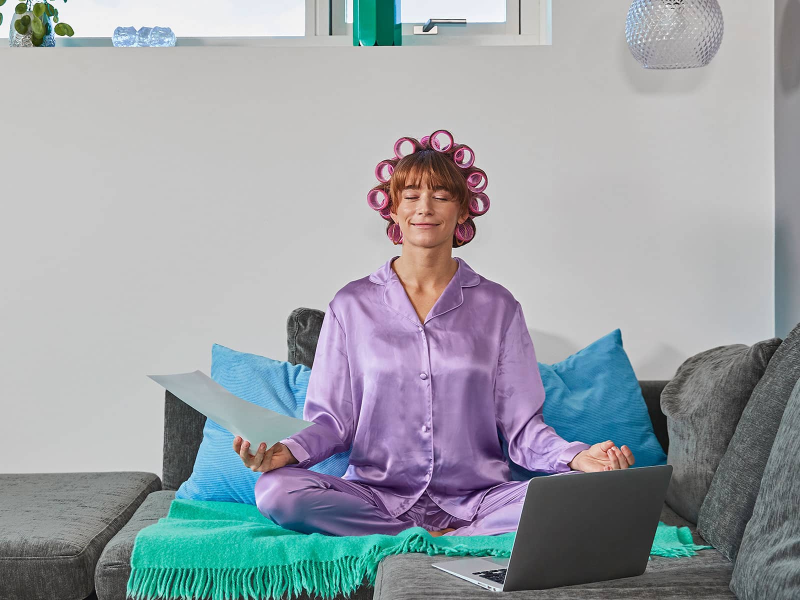 Kvinde i lilla pyjamas sidder i sin sofa med sin elregning. Hun er helt afslappet, da hun får el fra EWII med månedlig betaling.