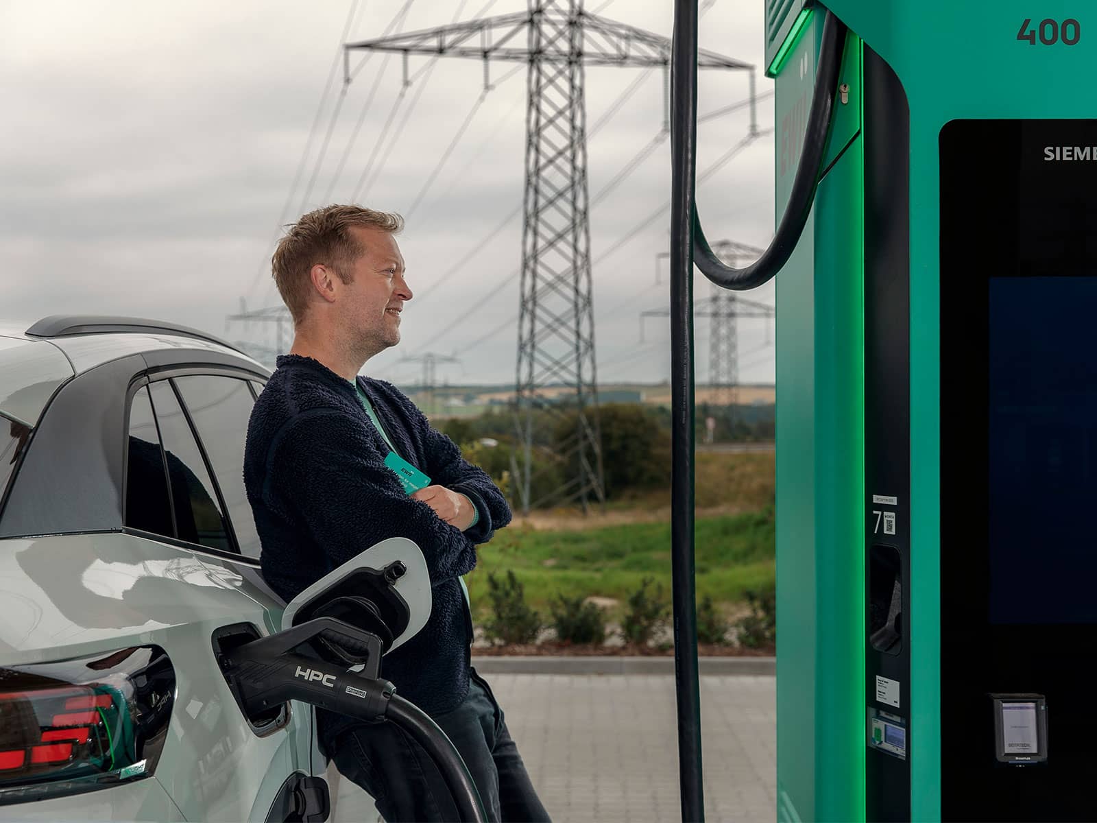 Mand læner sig op ad bil ved en EWII lynlader