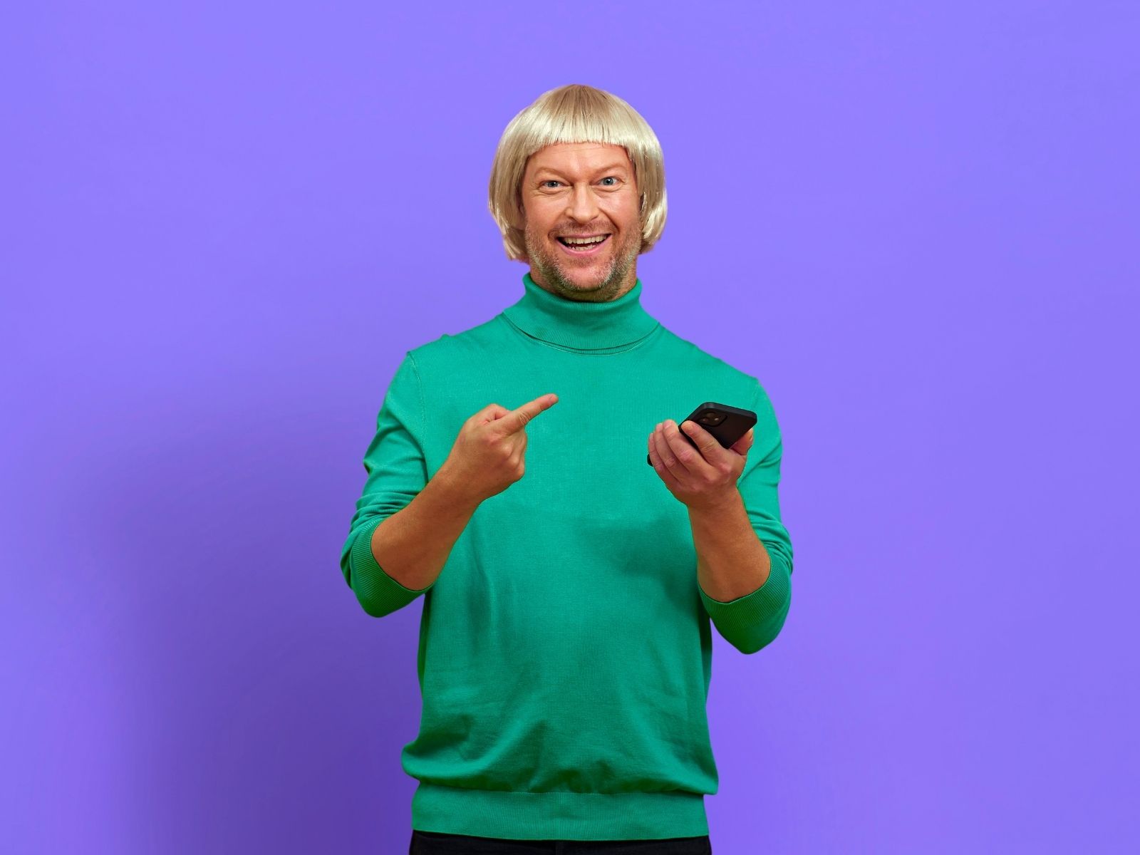 Mand smiler og peger på mobil