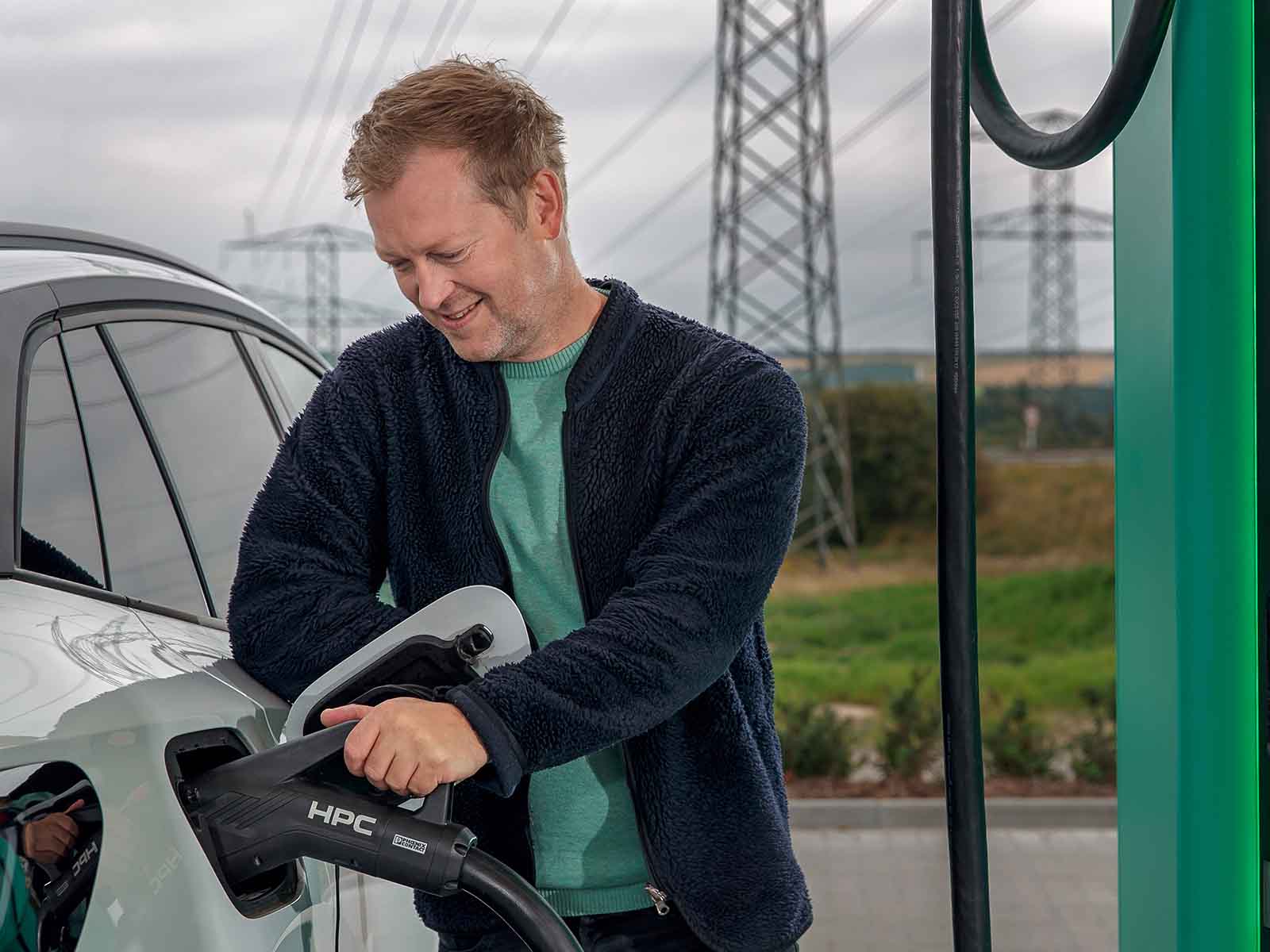 Mand tilslutter ladestik på elbil ved lynlader