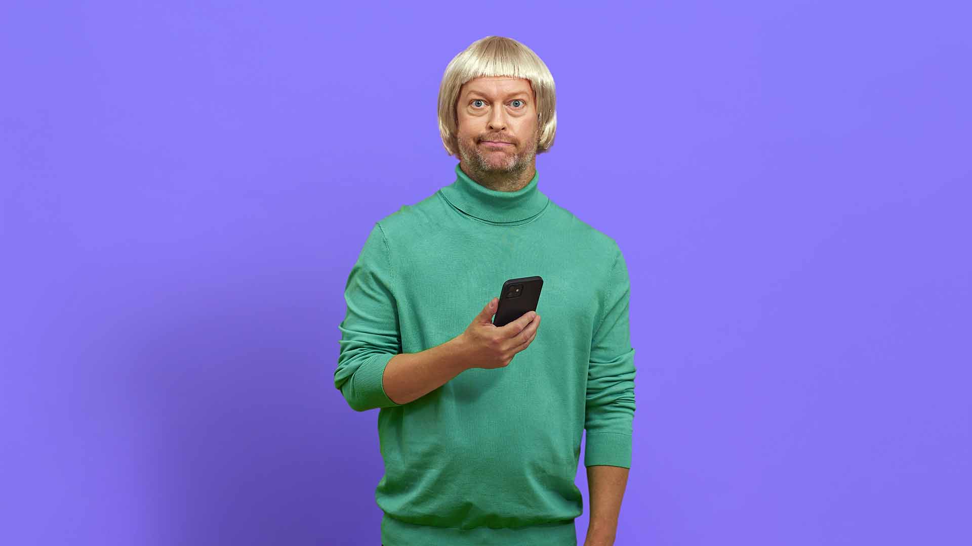 Mand med telefon i hånden ser forvirret ud, fordi han er ved at blive snydt på nettet af en falsk webshop. Få tips til sikker nethandel her.