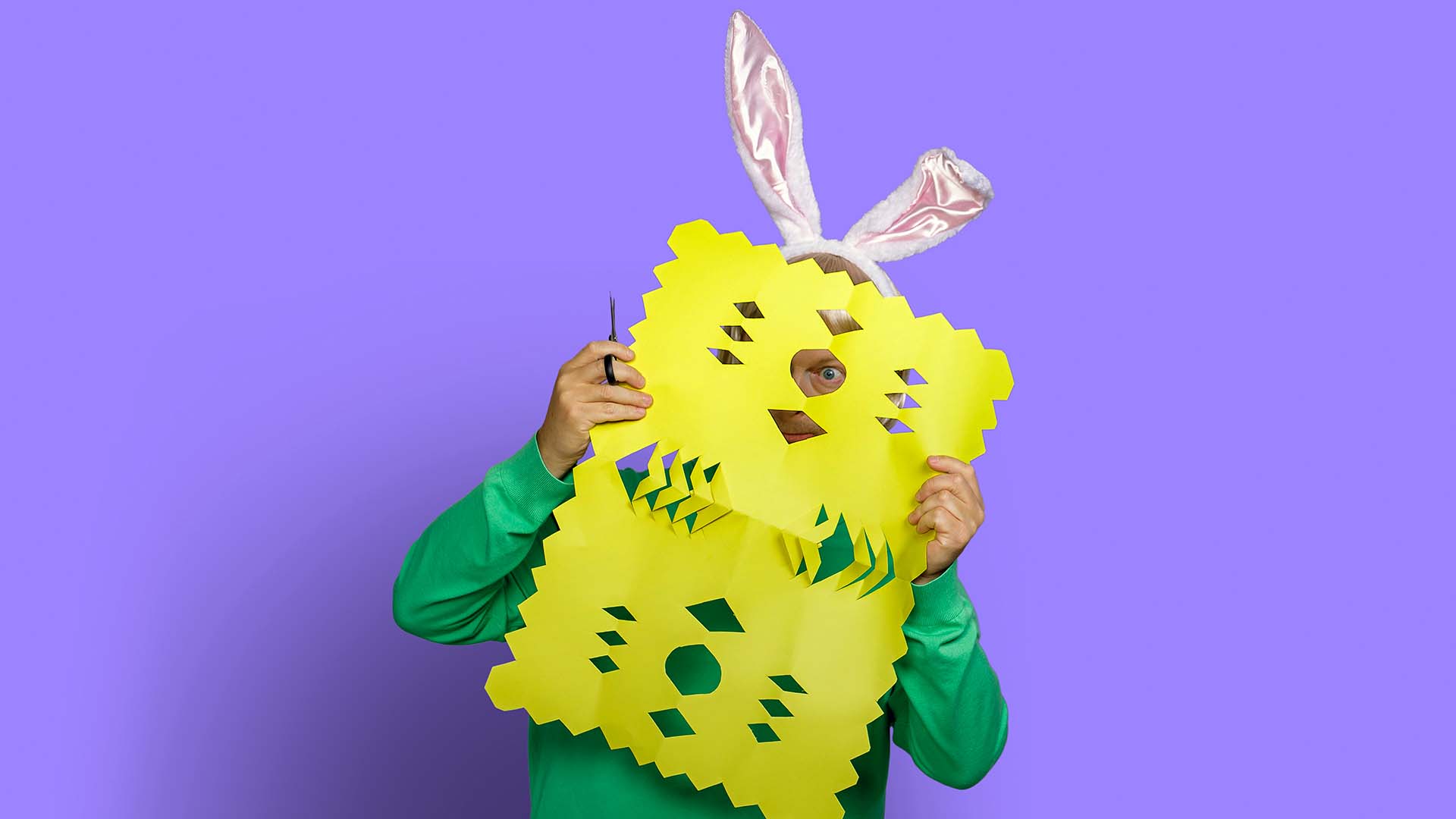 Mand står med gult gækkebrev foran sit ansigt. Spar 700 kr. på din elregning, når du bestiller el fra EWII i påsken.