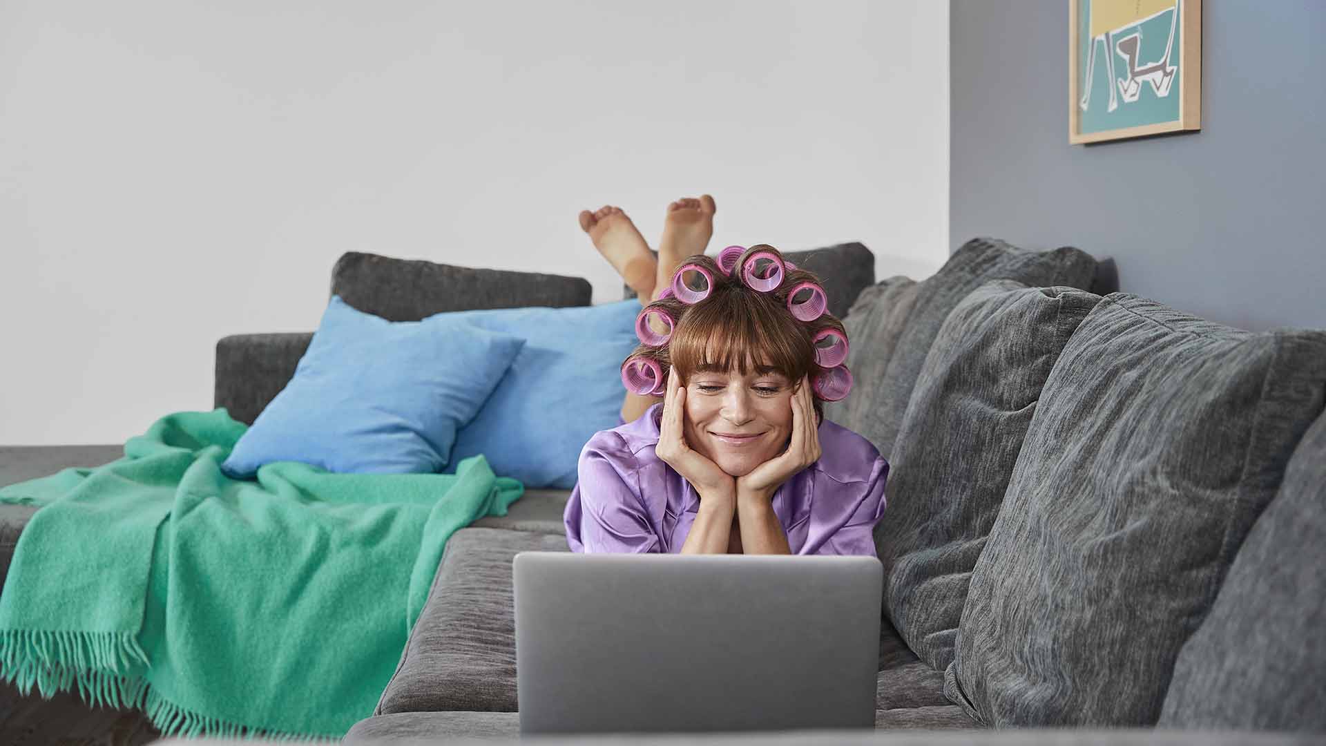 Kvinde ligger på maven i sofa og kigger på pc. Hun synes at internethastighed kan være svært. For hvilken internethastighed skal jeg vælge? Hvor mange mbit har jeg brug for? Ta' EWIIs internet test og få svar på 2 min.