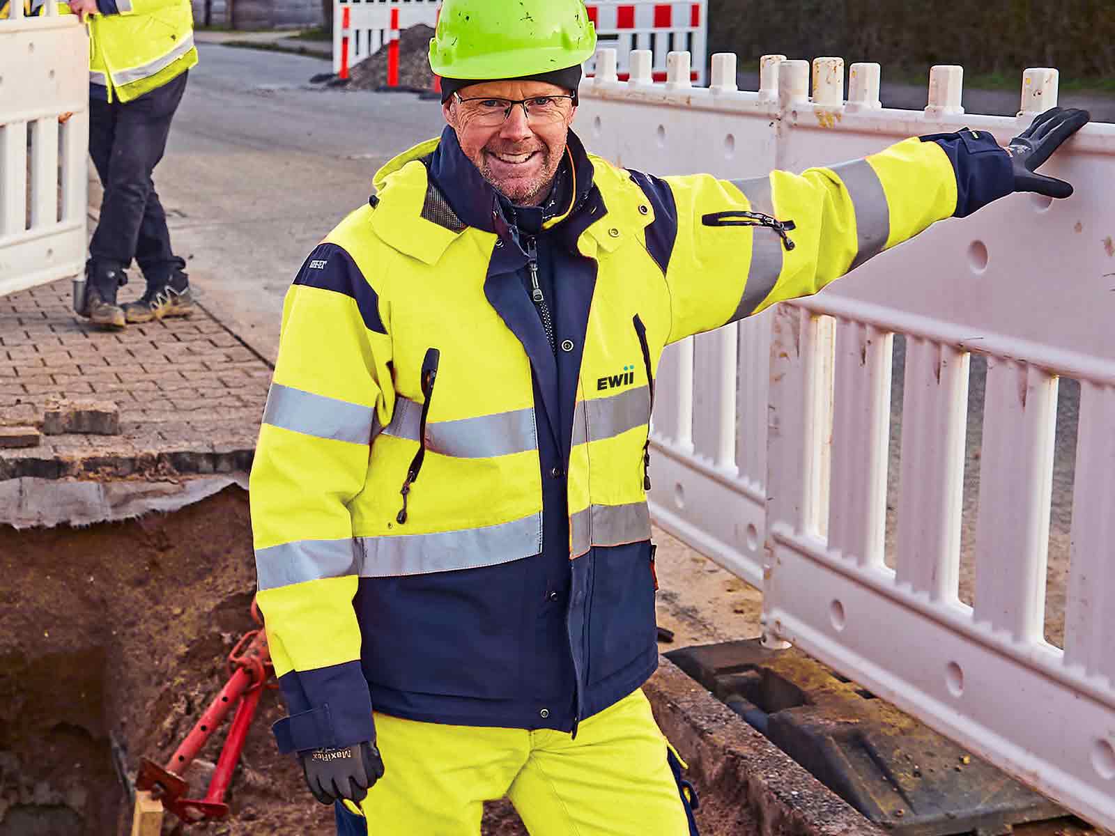 Glad EWII medarbejder står i gravehul ved vandrenoveringsprojekt.