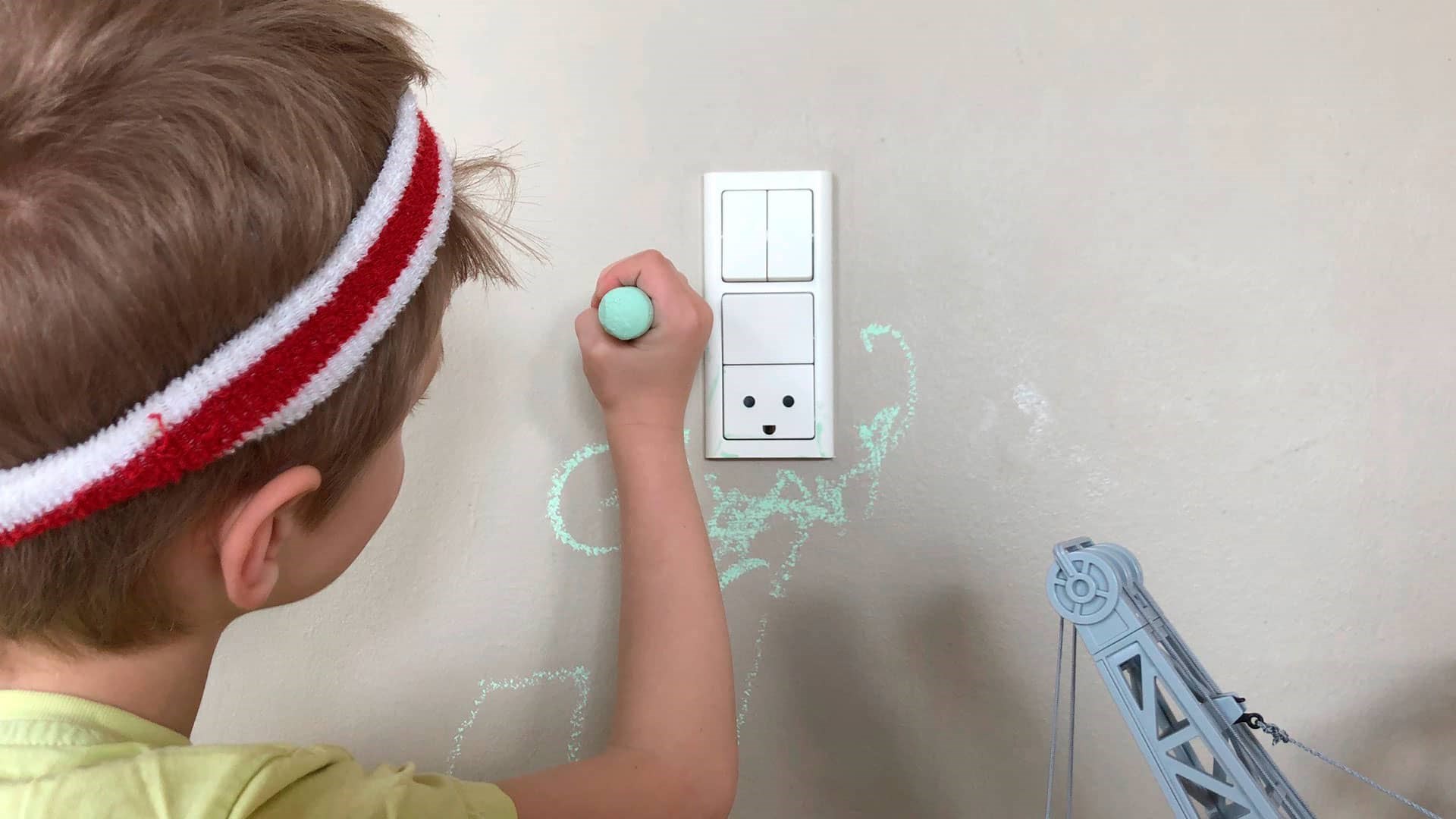 Dreng tegner med grønt kridt på væggen