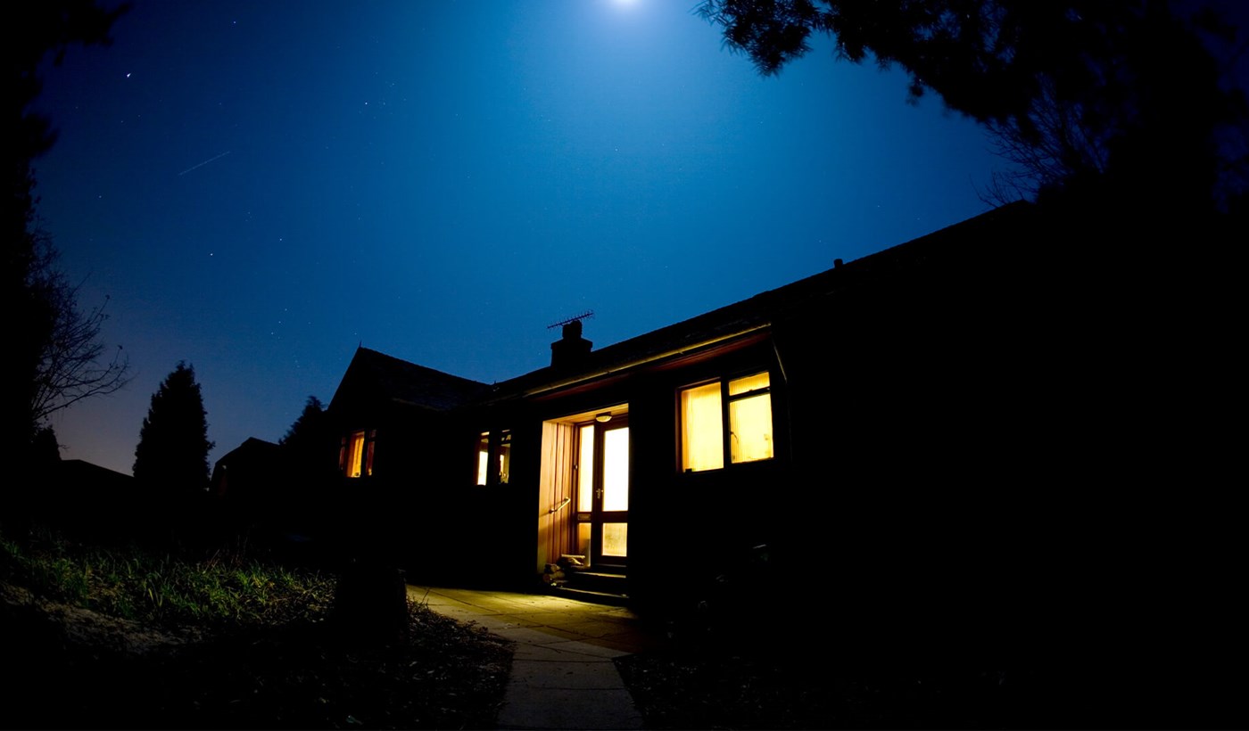 Hus i mørke med lys i vinduerne om aftenen. Få billig el fra EWII Energi.