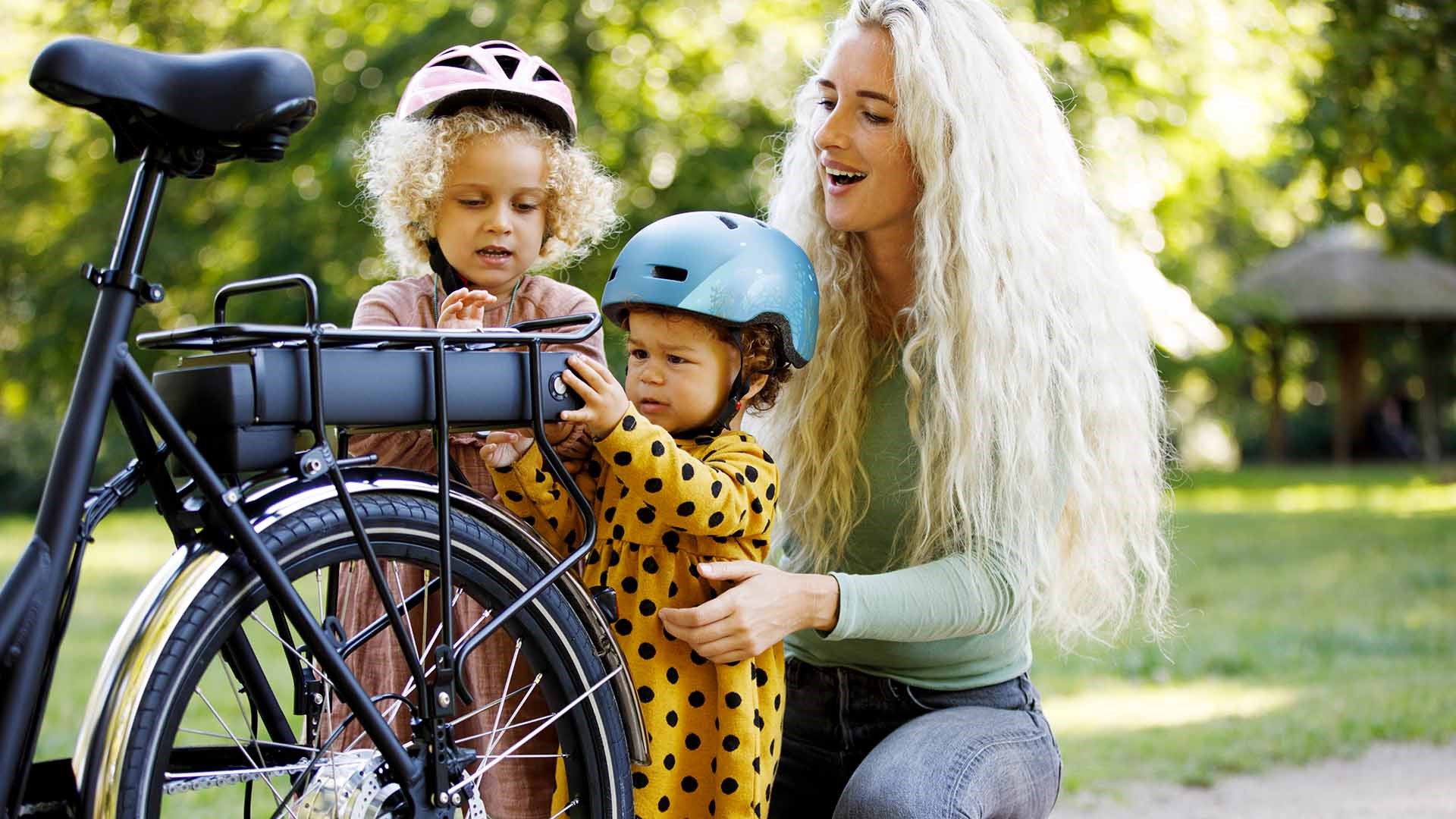 Kvinde og to børn med en elcykel. Hvad koster det at lade en elcykel op? Vi giver dig svaret her.