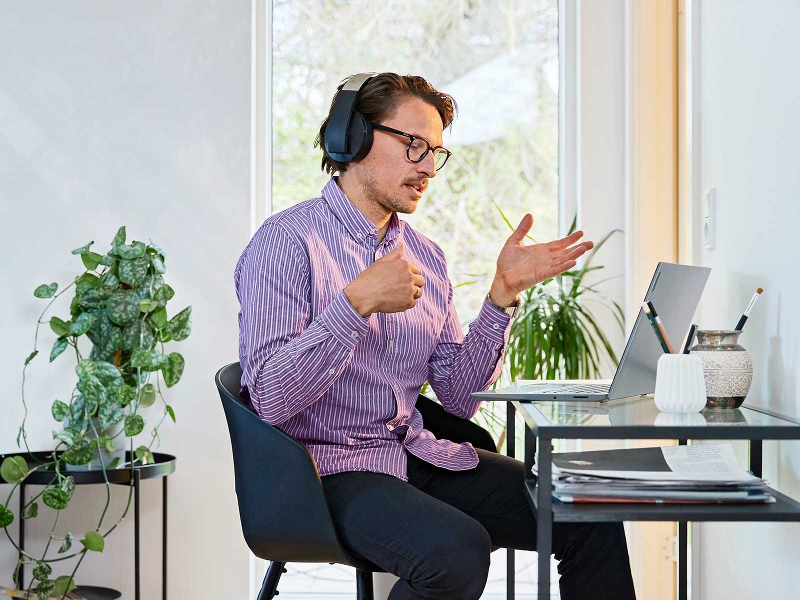 Mand sidder ved skrivebord med pc i online møde. Han bruger billigt bredbånd via fiberbredbånd til at arbejde hjemmefra.