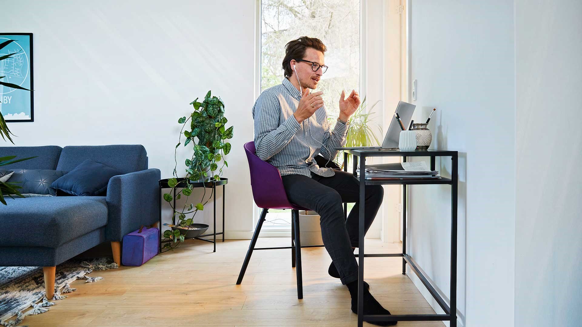 Mand sidder foran pc på sit hjemmekontor og afholder online møder. Han har fået gode råd til, hvordan han afholder online møder
