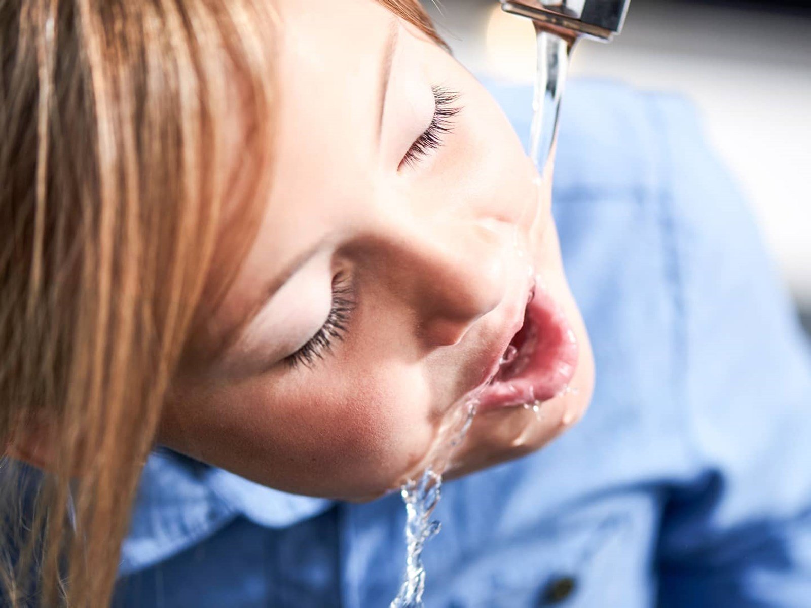 Pige drikker vand fra vandhanen