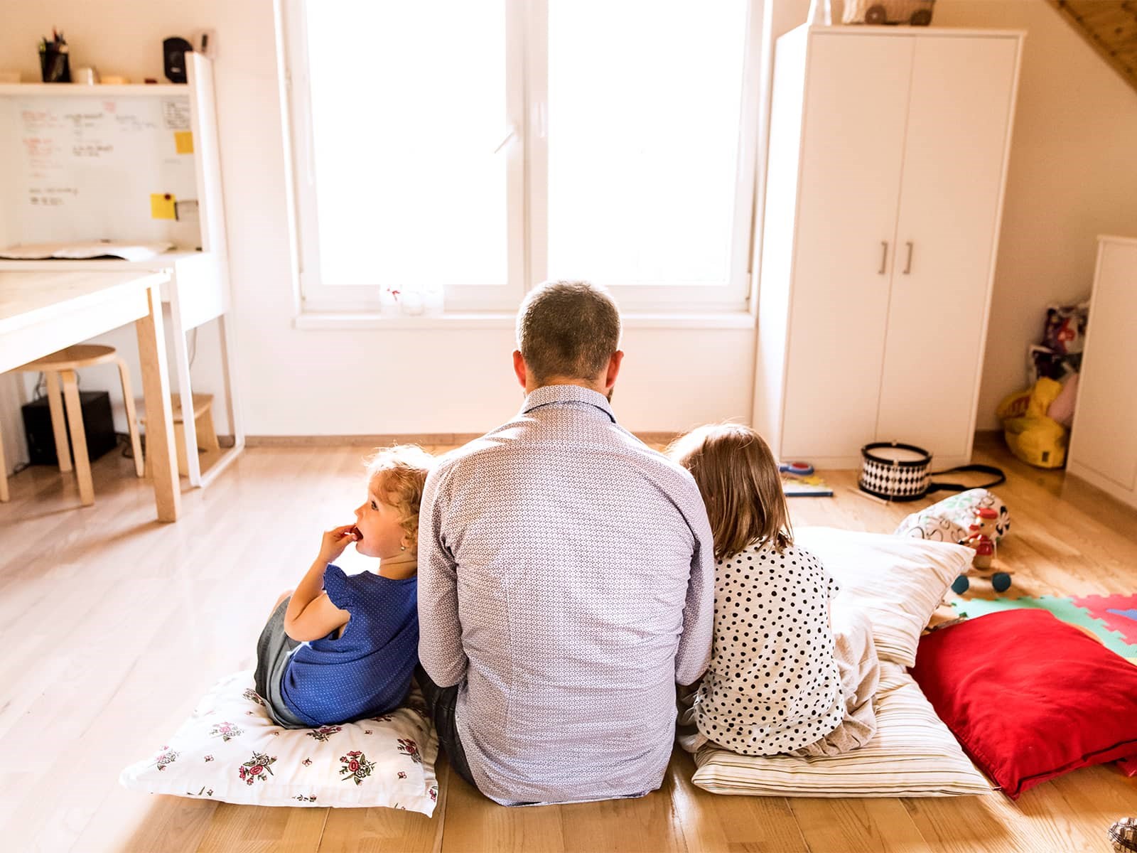 Far og børn ser ipad på gulvet. De har et godt indeklima i den udlejningsejendom de bor i.